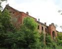 Zdjęcie przedstawia pałac w Gądnie. Na pierwszym planie widać fragment frontowej i bocznej elewacji. Budynek częściowo przysłonięty jest przez drzewa.                                                  