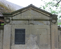 Zdjęcie przedstawia cmentarz przykościelny w Bielinie. Na pierwszym planie widać jedyny zachowany nagrobek. Po lewej stronie nagrobka znajduje się  płyta z czytelną inskrypcją.                        
