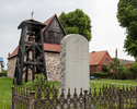 Zdjęcie przedstawia cmentarz przykościelny w Mielenku Gryfińskim. Na pierwszym planie widoczny jest pomnik dla ofiar I wojny światowej. W tle widać dzwon oraz fragment tylnej elewacji kościoła.       