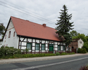 Zdjęcie przedstawia dom nr 6 w Starych Łysogórkach. Na pierwszym planie widać frontową i boczną elewację budynku. Na bocznej ścianie nie jest widoczna ryglowa konstrukcja.                             