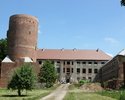 Zdjęcie przedstawia zamek w Swobnicy. Na pierwszym planie widać drogę prowadzącą do zamku. Po lewej stronie, nieco wysunięta jest  wieża. W centralnej części zdjęcia widać główne skrzydło zamku.      
