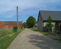Zdjęcie przedstawia główną drogę we wsi Borzyszkowo wraz z zabudowaniami.                                                                                                                               