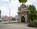 Zdjęcie przedstawia Bramę Portową w Szczecinie. Na pierwszym planie widać fragment placu przed zabytkiem i sam obiekt z frontu.                                                                         