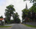 Zdjęcie przedstawia drogę wraz z kościołem i zabudowaniami we wsi Jeżyce.                                                                                                                               
