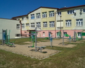 Zdjęcie przedstawia siłownię zewnętrzną w Postominie, znajdującą się przed budynkiem szkoły.                                                                                                            