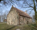 Zdjęcie przedstawia boczną ścianę oraz tył kościoła, który wykonany został z kamienia granitowego i cegły.                                                                                              