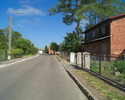Zdjęcie przedstawia główną drogę we wsi Naćmierz wraz zabudowaniami.                                                                                                                                    