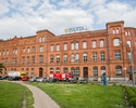 Zdjęcie przedstawia główny gmach Poczty Polskiej w Szczecinie. Na pierwszym planie widać fragment skweru przy pl. Tobruckim, dalej tylna elewacja budynku.                                              