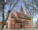 Zdjęcie przedstawia stronę boczną oraz tył kościoła, który został wykonany z czerwonej cegły.                                                                                                           