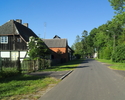Zdjęcie przedstawia drogę wraz z zabudowaniami we wsi Łącko.                                                                                                                                            