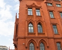 Zdjęcie przedstawia Ratusz Czerwony w Szczecinie. Na pierwszym planie widać boczną elewację budynku, po lewej stronie fragment filarów, które znajdują się przed głównym wejściem.                      