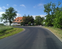 Zdjęcie przedstawia fragment drogi wraz z zabudowaniami we wsi Jezierzany.                                                                                                                              