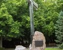 Zdjęcie przedstawia pomnik, który znajduje się na terenie Cmentarza Centralnego. Na pierwszym planie widać krzyż i tablicę z inskrypcją.                                                                