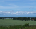 Zdjęcie przedstawia widok z Wzgórz Barzowickich w miejscowości Kopnica. Widoczne są wzgórza, jezioro Kopań i Bałtyk.                                                                                    