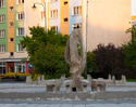Fotografia prxzedstawia fontannę na Placu Jana Pawła II na tle zieleni i budynków mieszkalnych..                                                                                                        