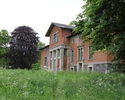 Zdjęcie przedstawia pałac w Bolkowicach. Na pierwszym planie widać polanę przed budynkiem, dalej zabytek w otoczeniu drzew.                                                                             