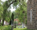 Zdjęcie przedstawia cmentarz przykościelny w Orzechowie. Na pierwszym planie widać nagrobki, po lewej stronie fragment kościoła.                                                                        