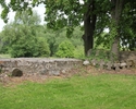 Zdjęcie przedstawia cmentarz przykościelny w Lubiechowie Górnym. Na pierwszym planie widać mur, który otacza nekropolię, w tle pomniki oparte o drzewo.                                                 