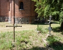 Zdjęcie przedstawia cmentarz przykościelny w Radziszewie. Na pierwszym planie widać przedwojenne groby z żeliwnymi krzyżami. W tle ściana kościoła.                                                     