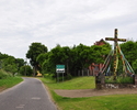 Widok z drogi wjazdowej do Bądkowa na osadę i witający podróżnych krzyż                                                                                                                                 