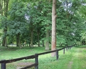 Zdjęcie przedstawia park w Stołecznej. Na pierwszym planie widać drewniany płot, w tle polana.                                                                                                          