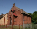 Na zdjęciu znajduje się strona wejścia oraz ściana boczna kościoła, który został zbudowany z cegły.                                                                                                     