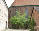 Zdjęcie przedstawia dawny klasztor augustiański w Chojnie. Na pierwszym planie widać zabudowania wokół klasztory, w tle tylna część zachowanego skrzydła.                                               