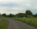 Zdjęcie przedstawia zabudowania we wsi Królewko wraz z drogą przebiegającą przez wieś.                                                                                                                  