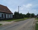 Zdjęcie przedstawia główną drogę we wsi Żukowo Morskie wraz z zabudowaniami.                                                                                                                            