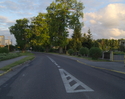 Zdjęcie przedstawia główną drogę we wsi Ostrowiec wraz z zabudowaniami. Z prawej strony drogi widoczna jest szkoła.                                                                                     