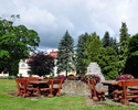 Zdjęcie przedstawia widok na park dworski wraz z roślinami rosnącymi na jego terenie oraz stoły i ławki służące do wypoczynku i spotkań                                                                 