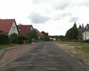 Zdjęcie przedstawia główną drogę we wsi Laki wraz z zabudowaniami.                                                                                                                                      