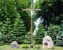 Zdjęcie przedstawia krzyż i głazy pamiątkowe stające w miejscu dawnego cmentarza przykościelnego w Karnicach                                                                                            