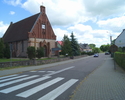 Zdjęcie przedstawia drogę we wsi Malechowo, na zdjęciu widoczny jest kościół i budynek Urzędu Gminy.                                                                                                    