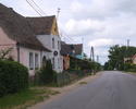 Zdjęcie przedstawia główna drogę we wsi Kwasowo wraz z zabudowaniami.                                                                                                                                   