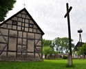 Zdjęcie przedstawia tył kościoła pw. MB Różańcowej w Gostyniu Łobeskim wraz z krzyżem stojącym na podwórzu.                                                                                             