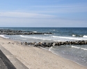 Zdjęcie przedstawia betonowe zejście na plażę oraz kamienne falochrony                                                                                                                                  