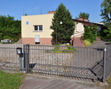 Zdjęcie przedstawia bramę wjazdową wraz z budynkiem sali królestwa świadków Jehowy przy ulicy Trzygłowskiej 30                                                                                          