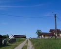 Zdjęcie przedstawia drogę i zabudowania we wsi Trzmielewo.                                                                                                                                              