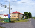 Zdjęcie przedstawia widok na jedną z ulic w Brojcach oraz budynki które znajdują się przy niej wraz z wjazdem na stadion drużyny Wicher Brojce                                                          