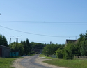 Zdjęcie przedstawia główną drogę we wsi Wilkowice wraz z zabudowaniami.                                                                                                                                 