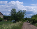 Zdjęcie przedstawia drogę we wsi Pieńkówko wraz z zabudowaniem.                                                                                                                                         