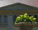 Zdjęcie przedstawia zbliżenie na front pałacu w Lekowie jako tło dla ozdobnego wazonu z kwiatami na podjeździe.                                                                                         