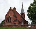 zdjęcie przedstawia kościół z czerwonej cegły, znajdujący się na wzniesieniu, otoczony niskim murem.                                                                                                    