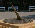 Zdjęcie przedstawia zbliżenie na zegar słoneczny stojący przy "Joasi"  w  parku w Połczynie-Zdroju.                                                                                                     