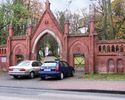 Zdjęcie przedstawia bramę cmentarną wykonaną z czerwonej cegły.                                                                                                                                         