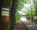 Zdjęcie przedstawia oznakowanie szlaku na drzewie oraz wiaty drewniane                                                                                                                                  