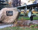 Zdjęcie pokazuje pamiątkowy głaz z tablicą i fragmentem samolotu wojskowego                                                                                                                             