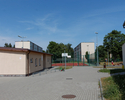 Zdjęcie przedstawia budynki i boisko do koszykówki na orliku przy ulicy Dobrzańskiej.                                                                                                                   