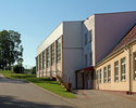 Zdjęcie przedstawia halę sportową w Rąbinie w widoku od strony wschodniej. W tle boisko Orlik.                                                                                                          